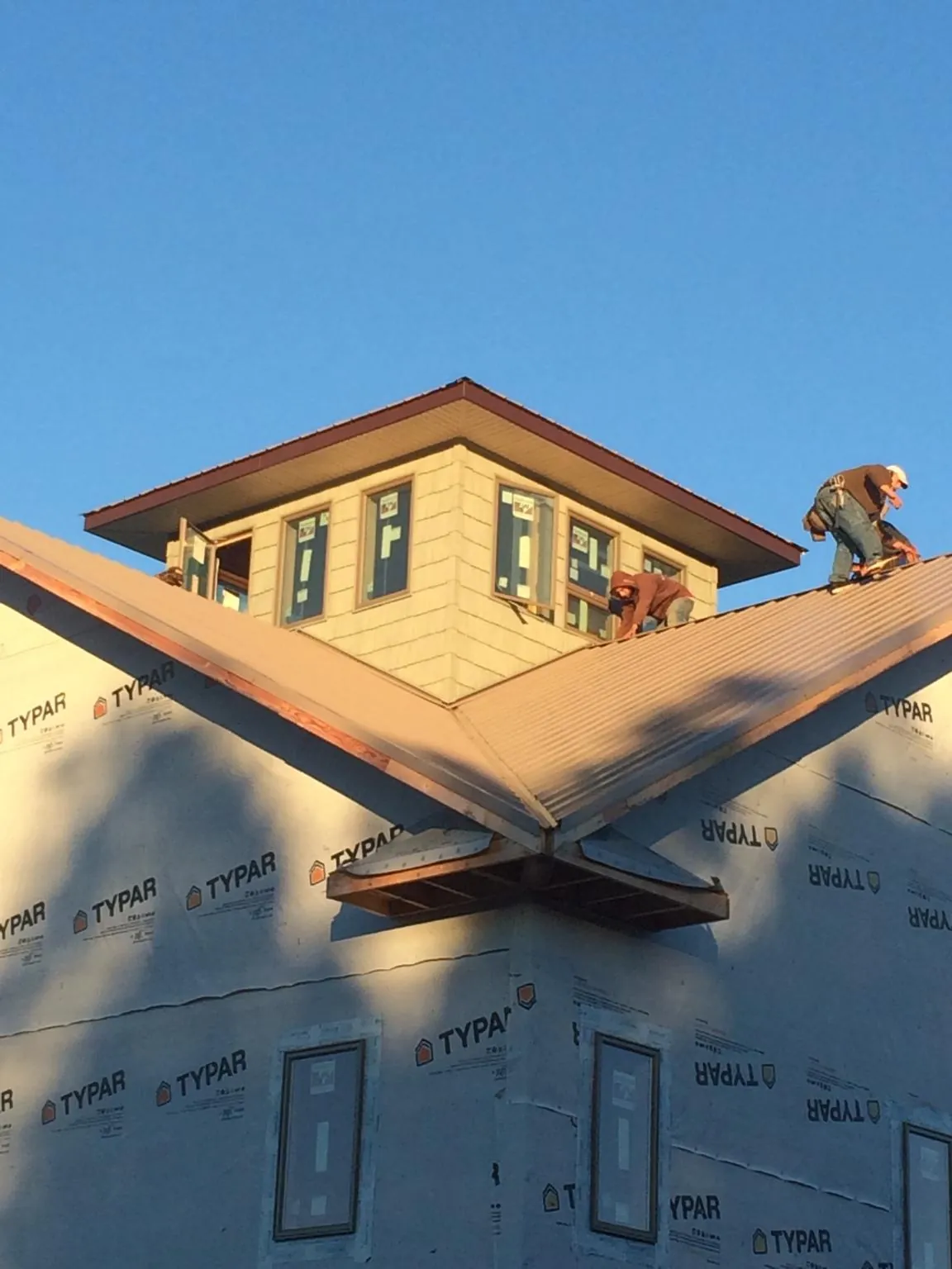 Roofers working around a rooftop cupola on a new metal roof at sunset — Roof Waterproofing in Loretto by Roofing Brothers